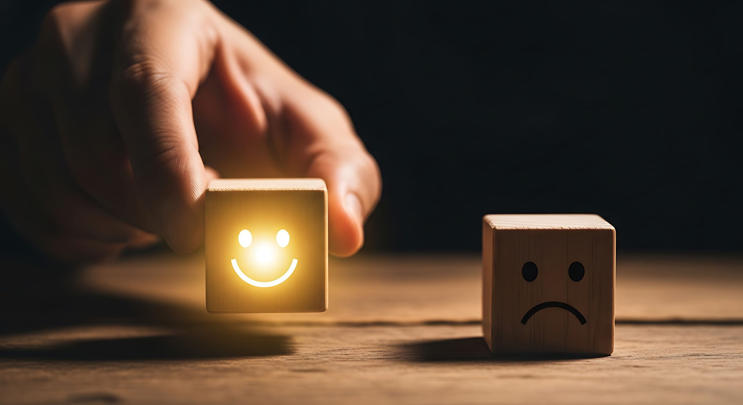 A hand replaces a frowning face emoticon with a smiling face emoticon on wooden blocks, symbolizing a positive customer experience or mood change.